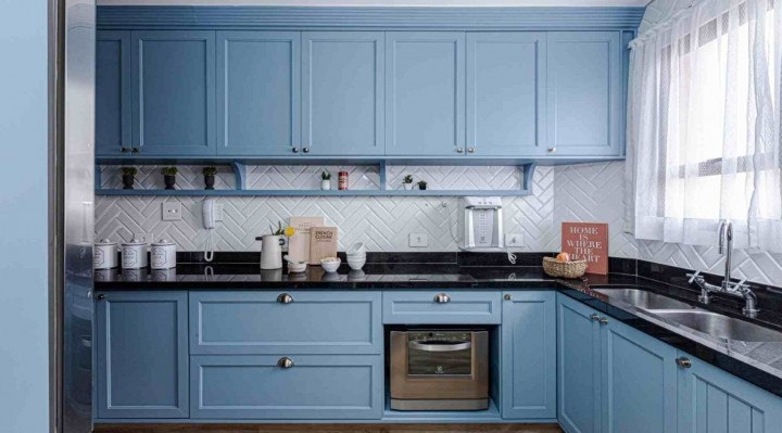 Cozinha ganhou uma marcenaria clássica e atual, marcada pelo uso do azul e de puxadores com formato concha.