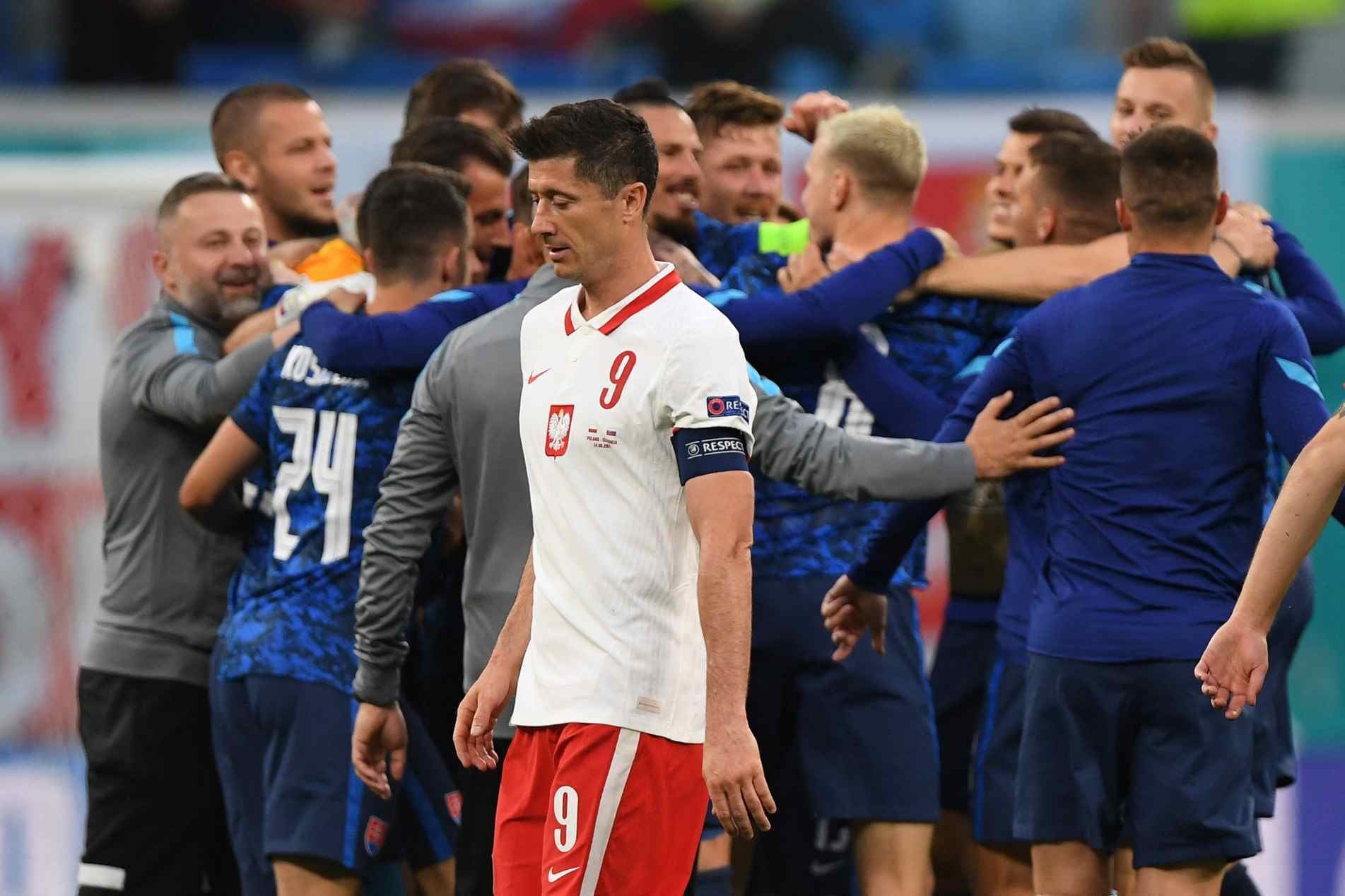 Lewandowski cabisbaixo enquanto jogadores da Eslováquia comemoram vitória