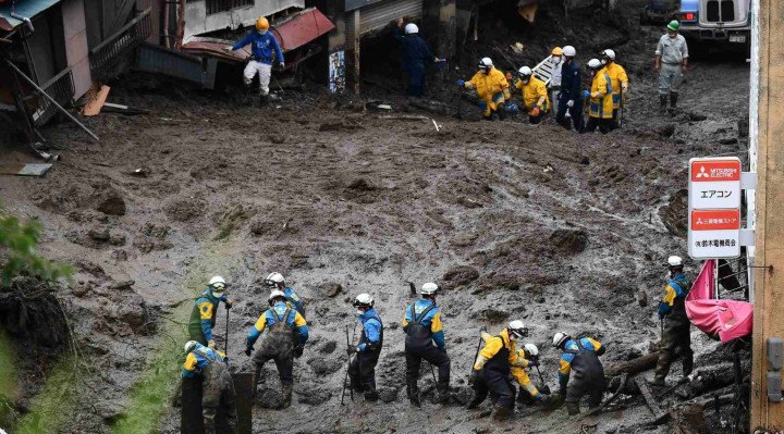 Bombeiros e soldados, com o auxílio de máquinas, tentam encontrar sobreviventes do deslizamento, em meio à lama 
