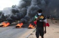 Um manifestante sudanês veste a bandeira nacional enquanto faz o símbolo 'V' de vitória com as mãos - AFP
