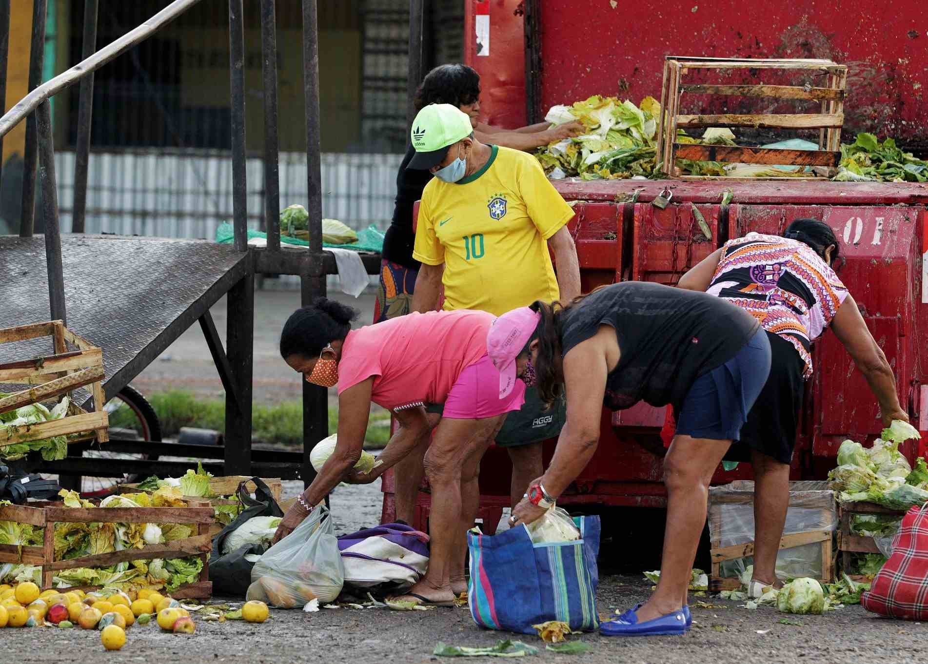 Pessoas pegam frutas e verduras descartadas, em Belém 