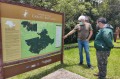 O monitor ambiental Anderson de Queiroz Domingues (direita) esclarece as dúvidas do visitante sobre as trilhas apresentadas em placa interpretativa. - DIVULGAÇÃO