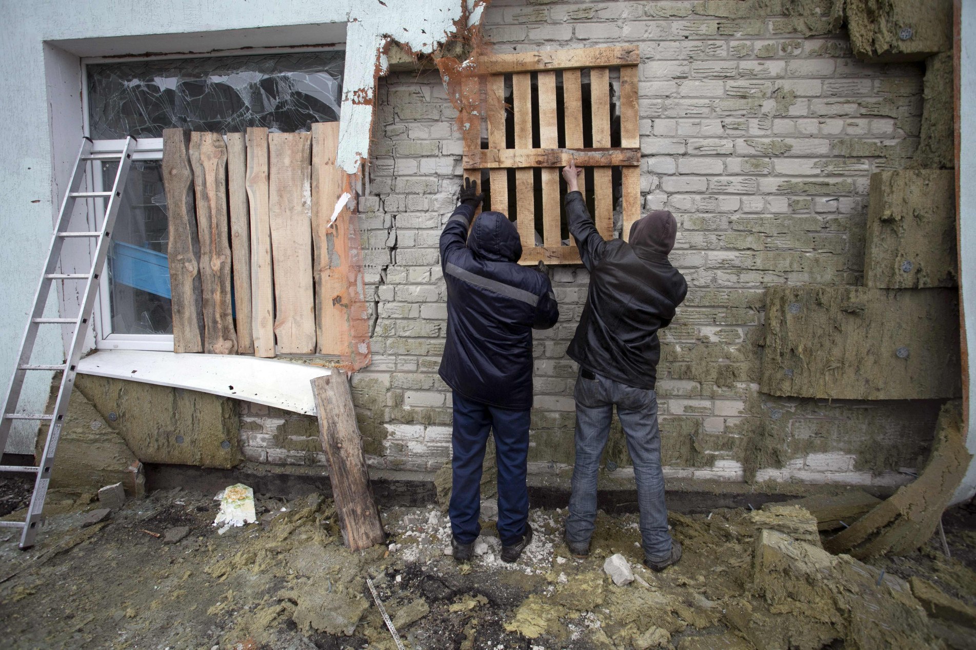 Ucranianos reparam casa após bombardeio de separatistas.