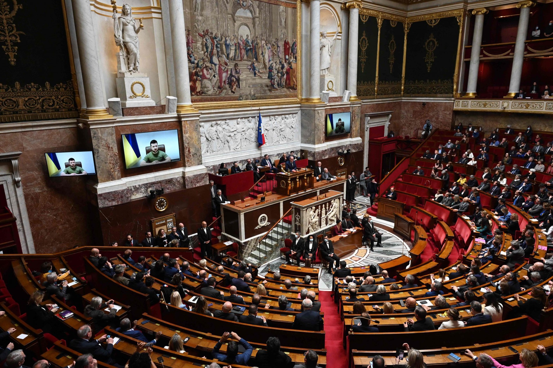 Deputados franceses acompanham Zelensky pelo telão.