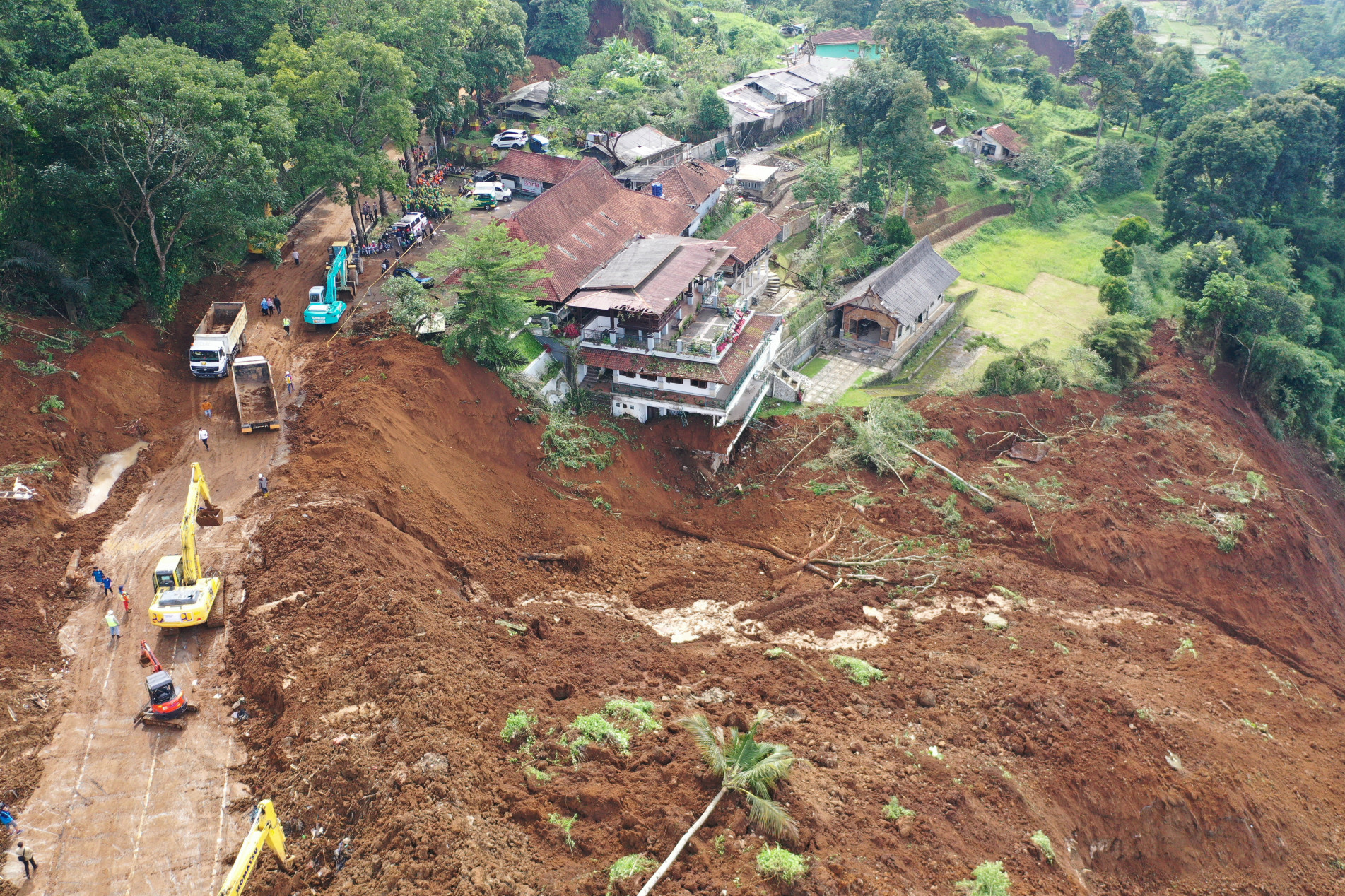  This aerial photo shows workers (L) using heavy equipments to remove soil following landslide triggered by a 5.6-magnitude earthquake near Cianjur on November 22, 2022. - The death toll from an earthquake on Indonesia's main island of Java jumped to 268 on November 22, as rescuers searched for survivors in the rubble and relatives started to bury their loved ones. (Photo by ADEK BERRY / AFP)