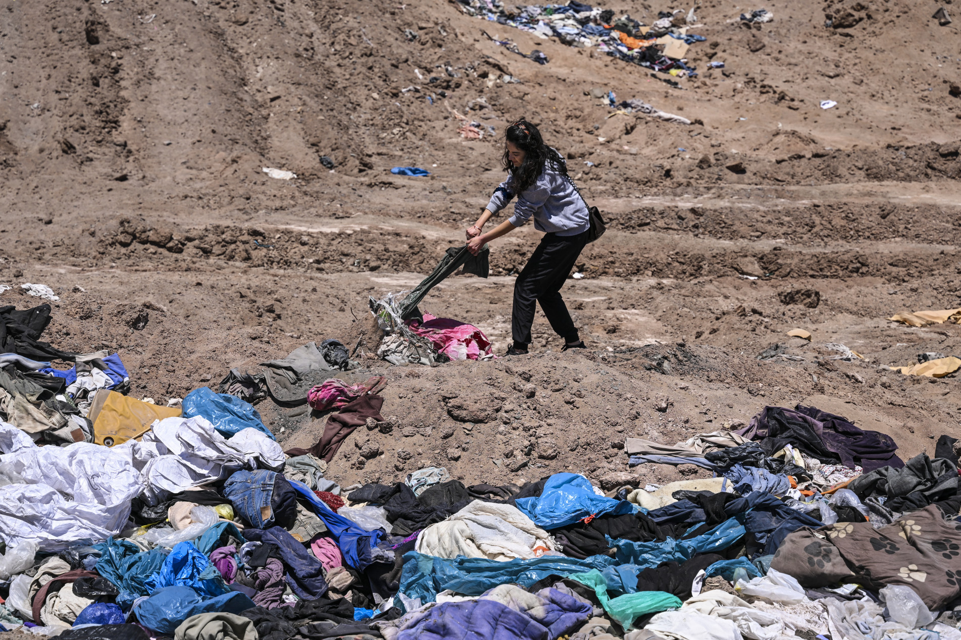  Lawyer Paulina Silva shows clothes dumped in the desert, in La Pampa sector of Alto Hospicio, about 10 km east of the city of Iquique, Chile, on November 11, 2022. - Hills of clothes from the United States, Asia and Europe; used cars from Japan or Korea and thousands of tires contaminate extensive areas of the immense but vulnerable Atacama desert in northern Chile, which has become the planet's 