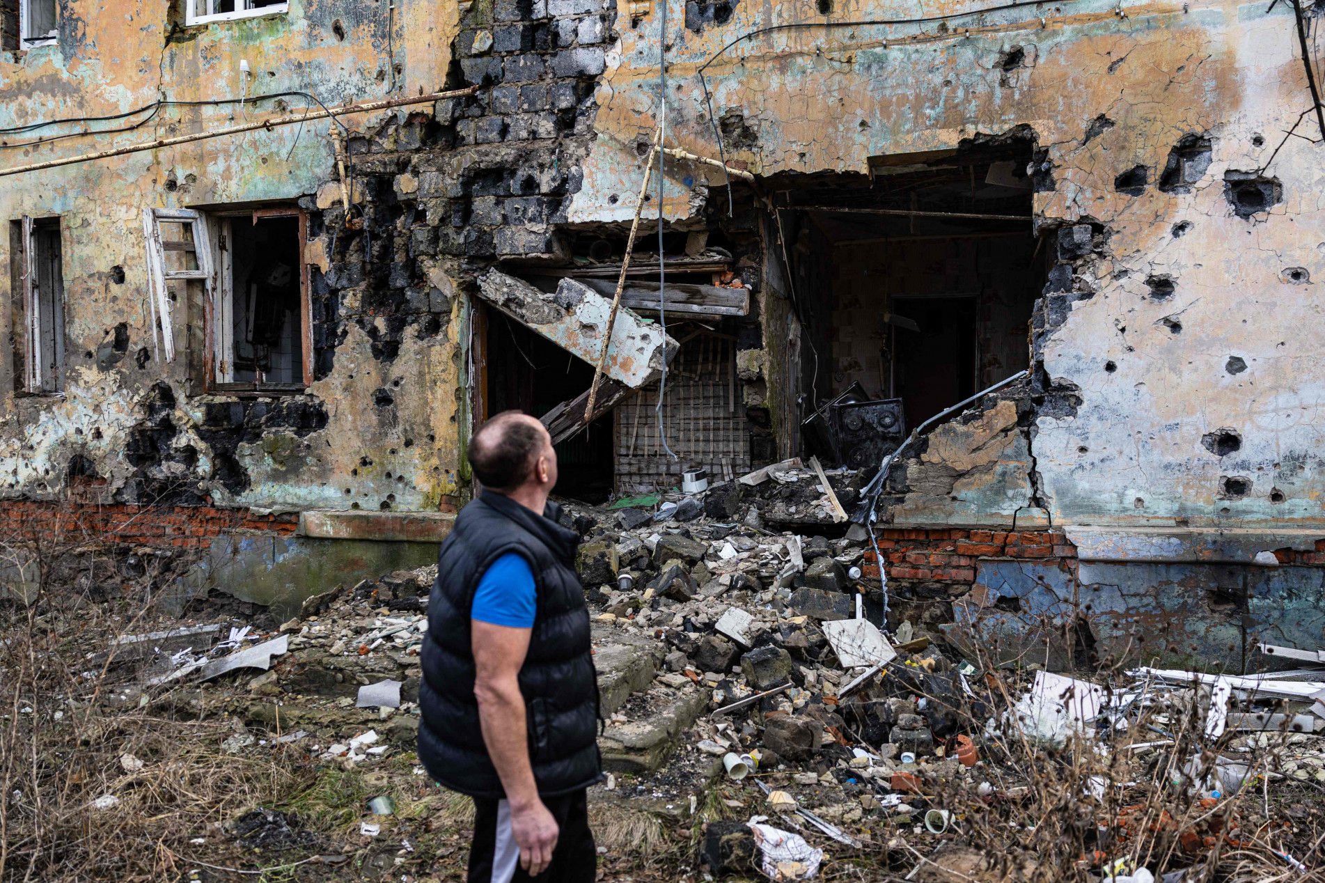 Homem observa destruição num prédio na região de Donetsk