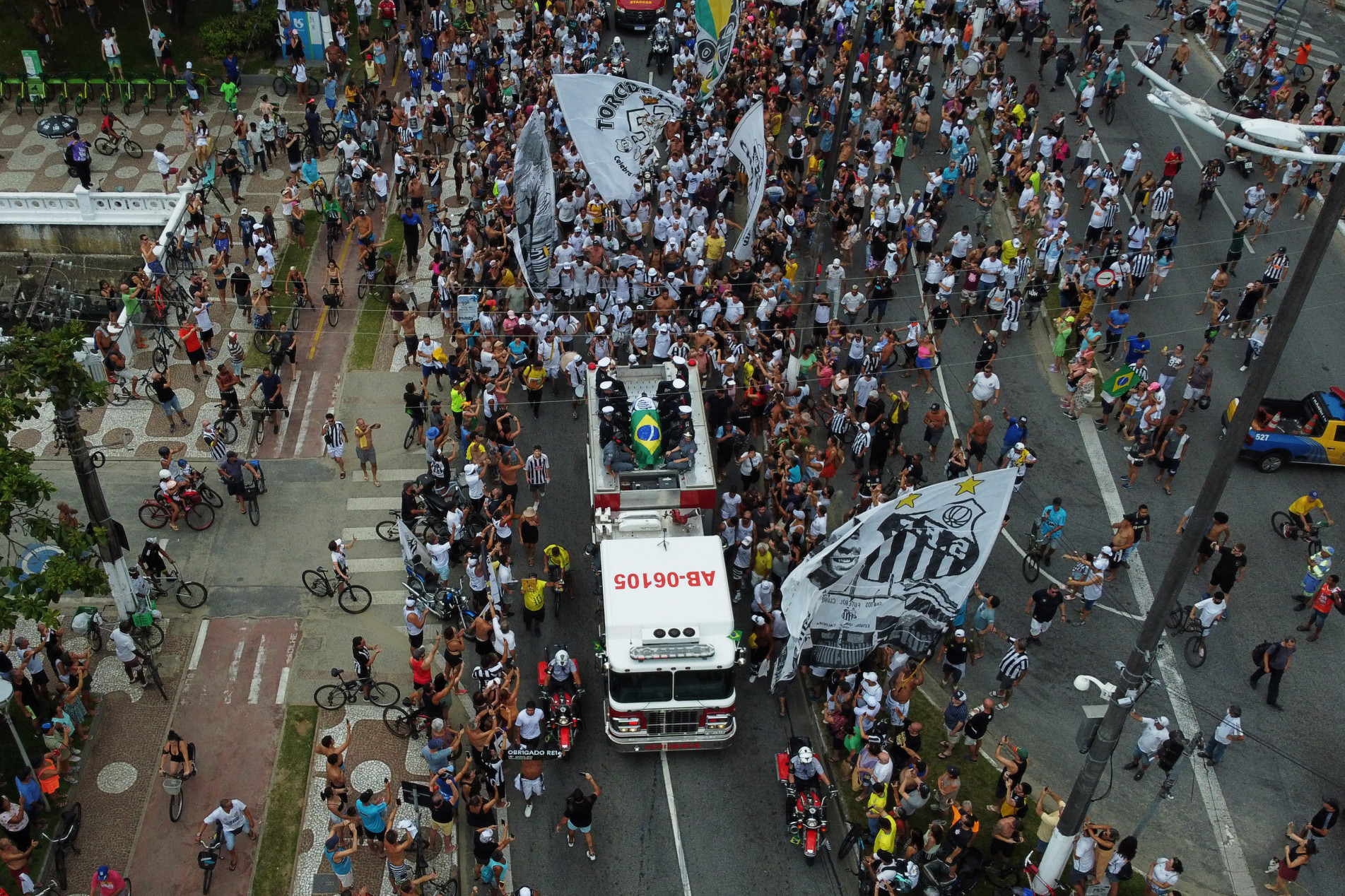  In this aerial picture fans of the late Brazilian football star Pele gather on the street as a firetruck transports Pele's coffin to the Santos' Memorial Cemetery in Santos, Sao Paulo state, Brazil on January 3, 2023. - The funeral procession through Santos will go past the house of Pele's mother, 100-year-old Celeste Arantes, who is still alive. It will end at Santos's Memorial Cemetery, where a Catholic funeral service will be held before Pele is interred in a special mausoleum. (Photo by Miguel SCHINCARIOL / AFP)