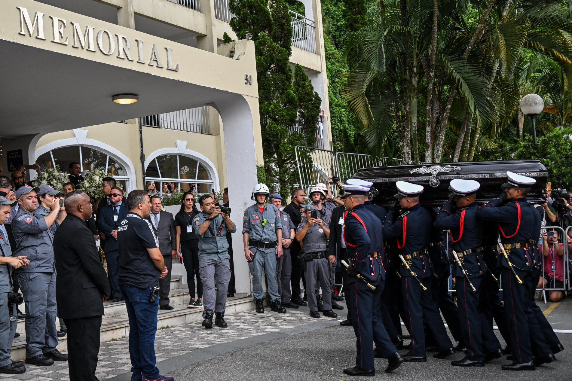  The coffin of the late Brazilian football star Pele arrives to the Santos' Memorial Cemetery after the funeral procession in Santos, Sao Paulo state, Brazil on January 3, 2023. - Brazilian football legend Pele's remains arrived Tuesday at the cemetery where he will be interred in a mausoleum, after three days of national mourning, a 24-hour wake and a massive funeral procession. Pele's casket, draped in the Brazilian flag and that of his longtime club, Santos FC, arrived atop a red firetruck at the Santos Memorial Cemetery, near the stadium where 