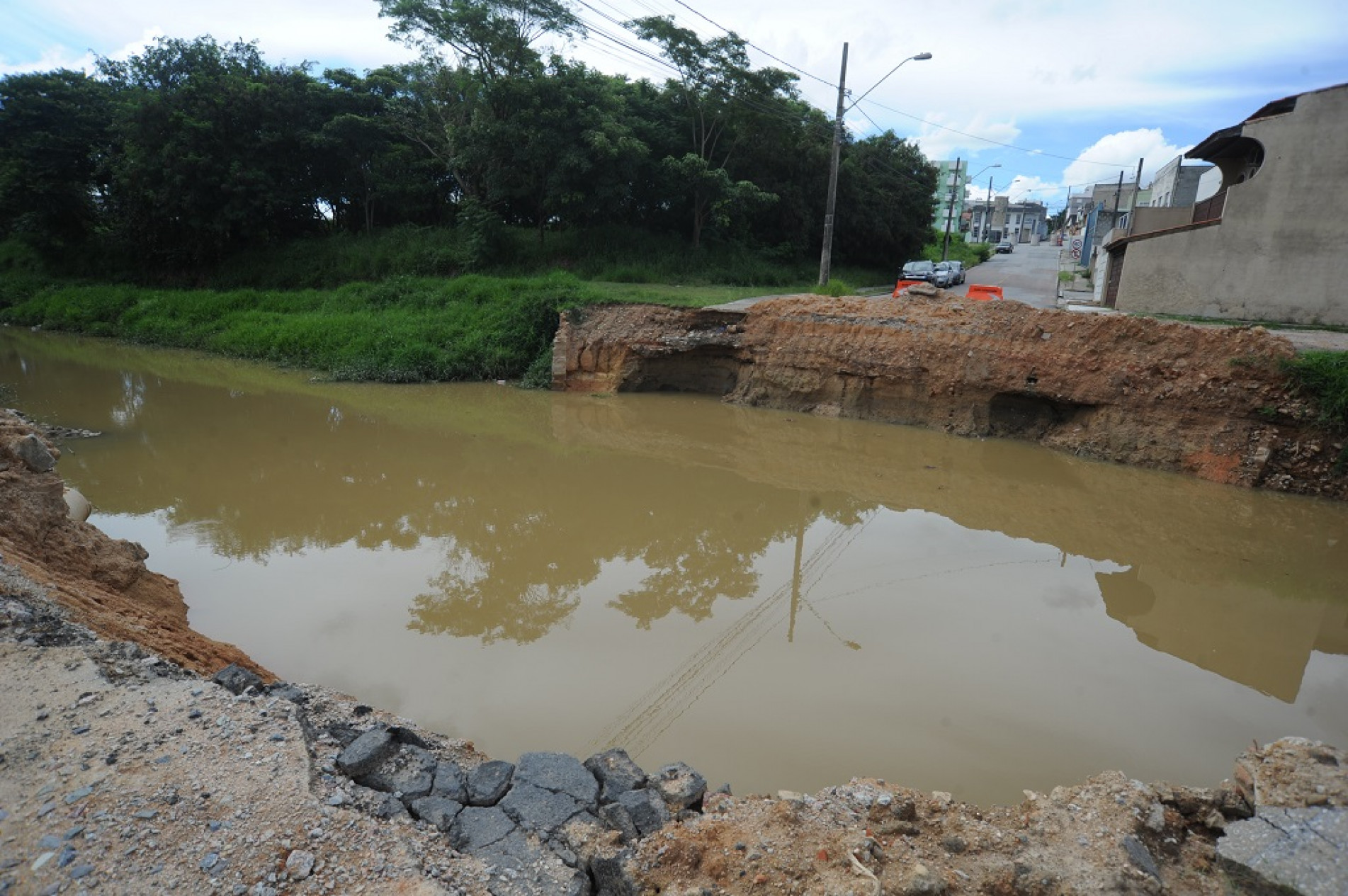 A rua, anteriormente asfaltada, virou um córrego com as chuvas de verão