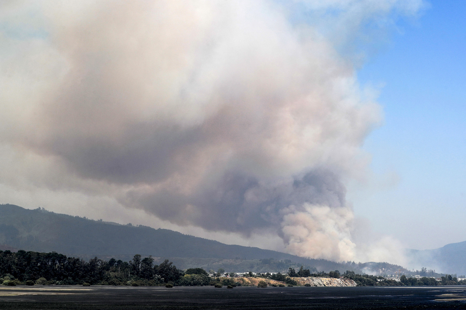  Smoke rises from a fire in Santa Juana, Concepcion province, Chile on February 3, 2023. - Chile has declared a state of disaster in several central-southern regions after a devastating heat wave provoked forest fires that left four people dead, authorities said on Friday. (Photo by JAVIER TORRES / AFP)
      Caption