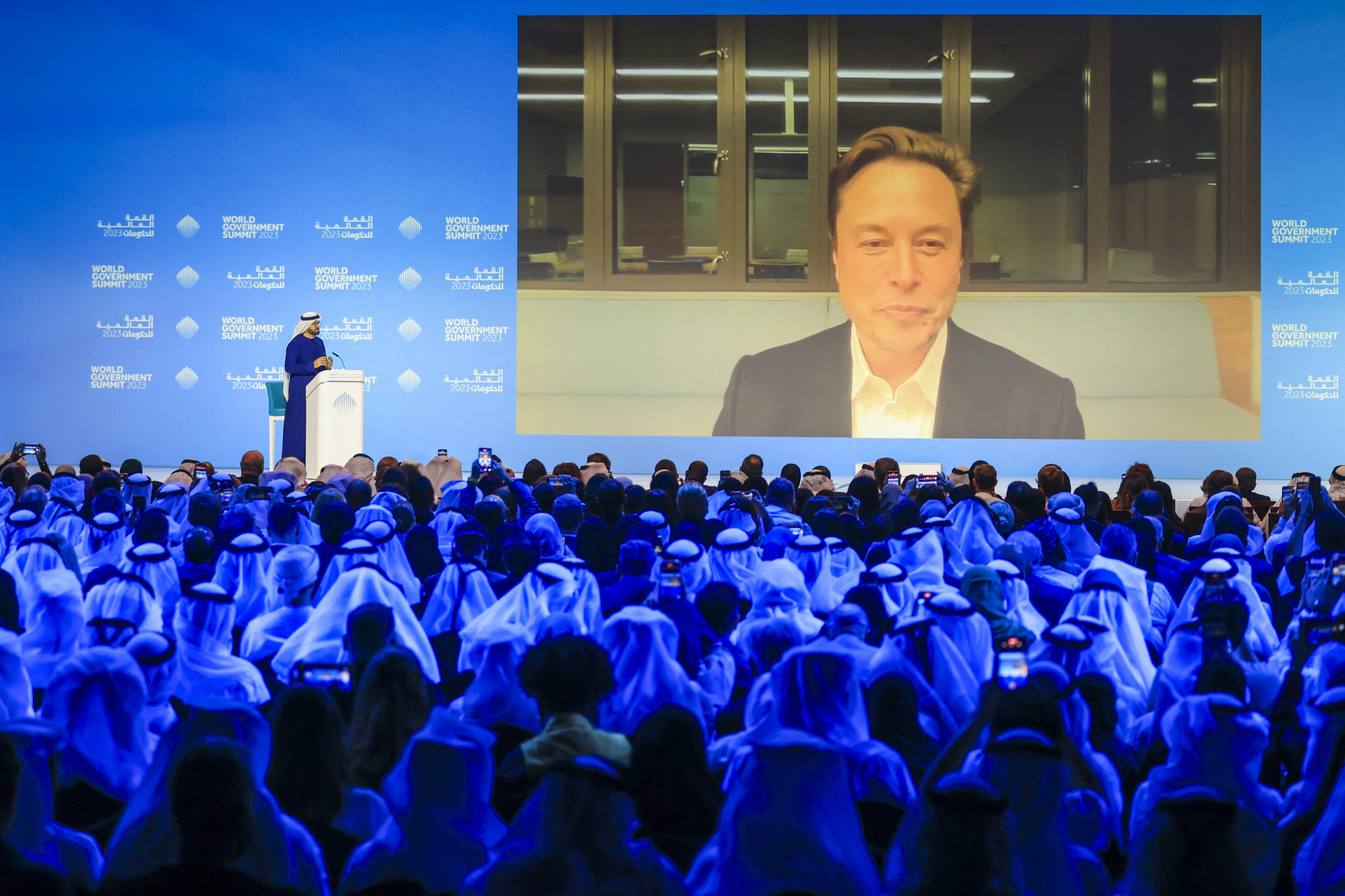  UAE Minister of Cabinet Affairs Mohammad al-Gergawi (L-on stage) speaks with Elon Musk attending the World Government Summit virtually in Dubai on February 15, 2023. (Photo by Karim SAHIB / AFP)