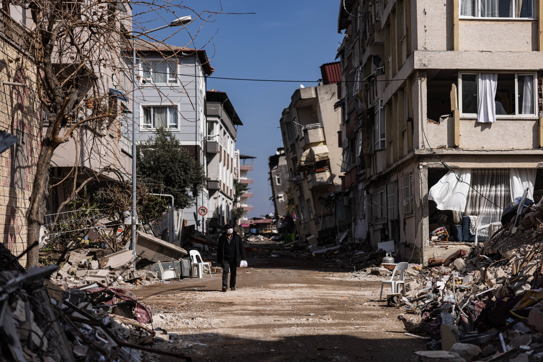  Kahraman, 62, walks past collapsed building after a 6.4-magnitude earthquake hit the Hatay province in southern Turkey, in Antakya, on February 21, 2023. - The 6.4-magnitude earthquake struck on February 20, two weeks after a 7.8-magnitude quake hit near Gaziantep, Turkey, in the early hours of February 6, followed by another 7.5-magnitude tremor just after midday. The initial quakes caused widespread destruction in southern Turkey and northern Syria and has killed more than 44,000 people. (Photo by Sameer Al-DOUMY / AFP)
