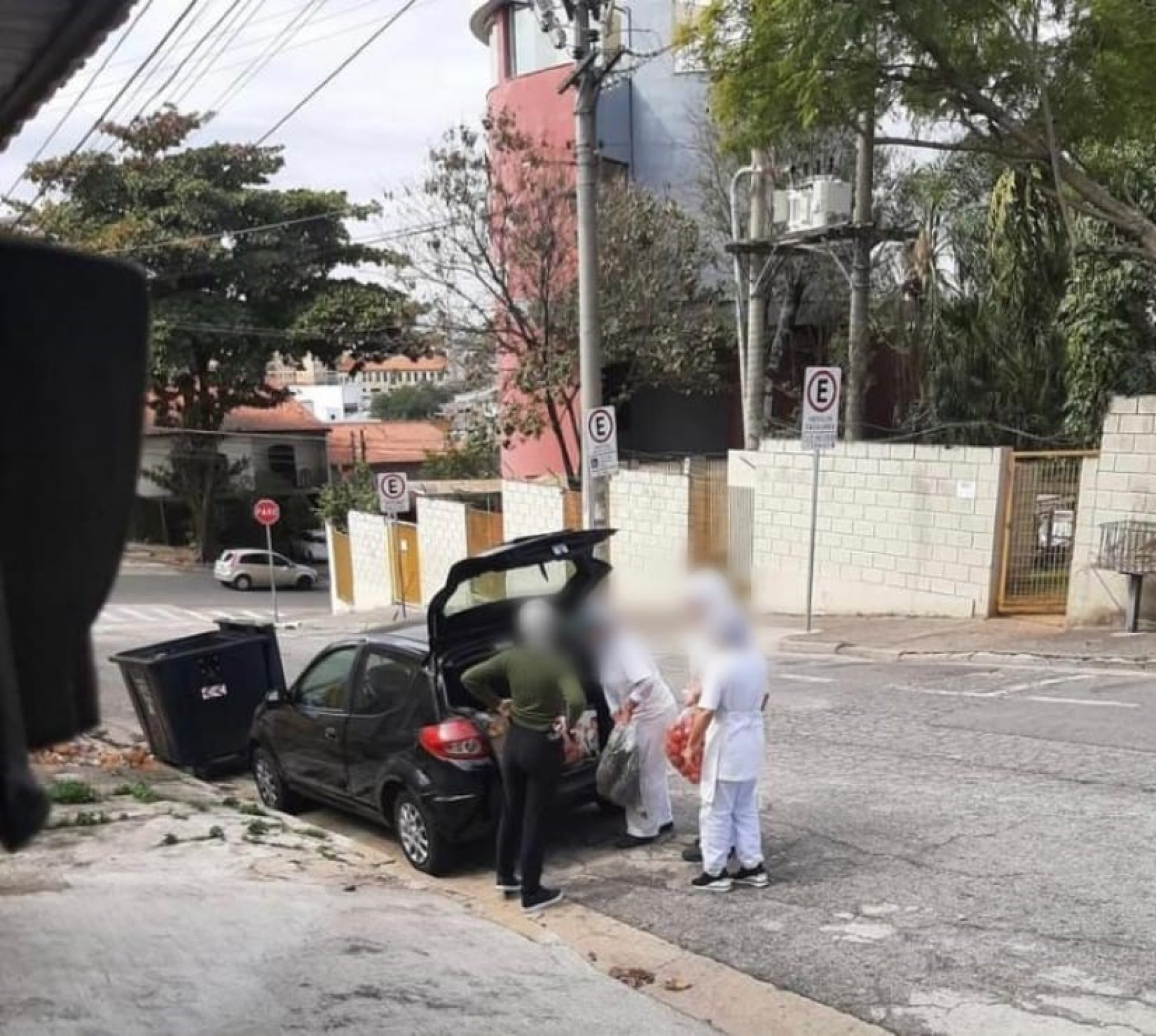 Foto mostra nutricionista e cozinheiras fazendo transporte de alimentos de uma escola para outra