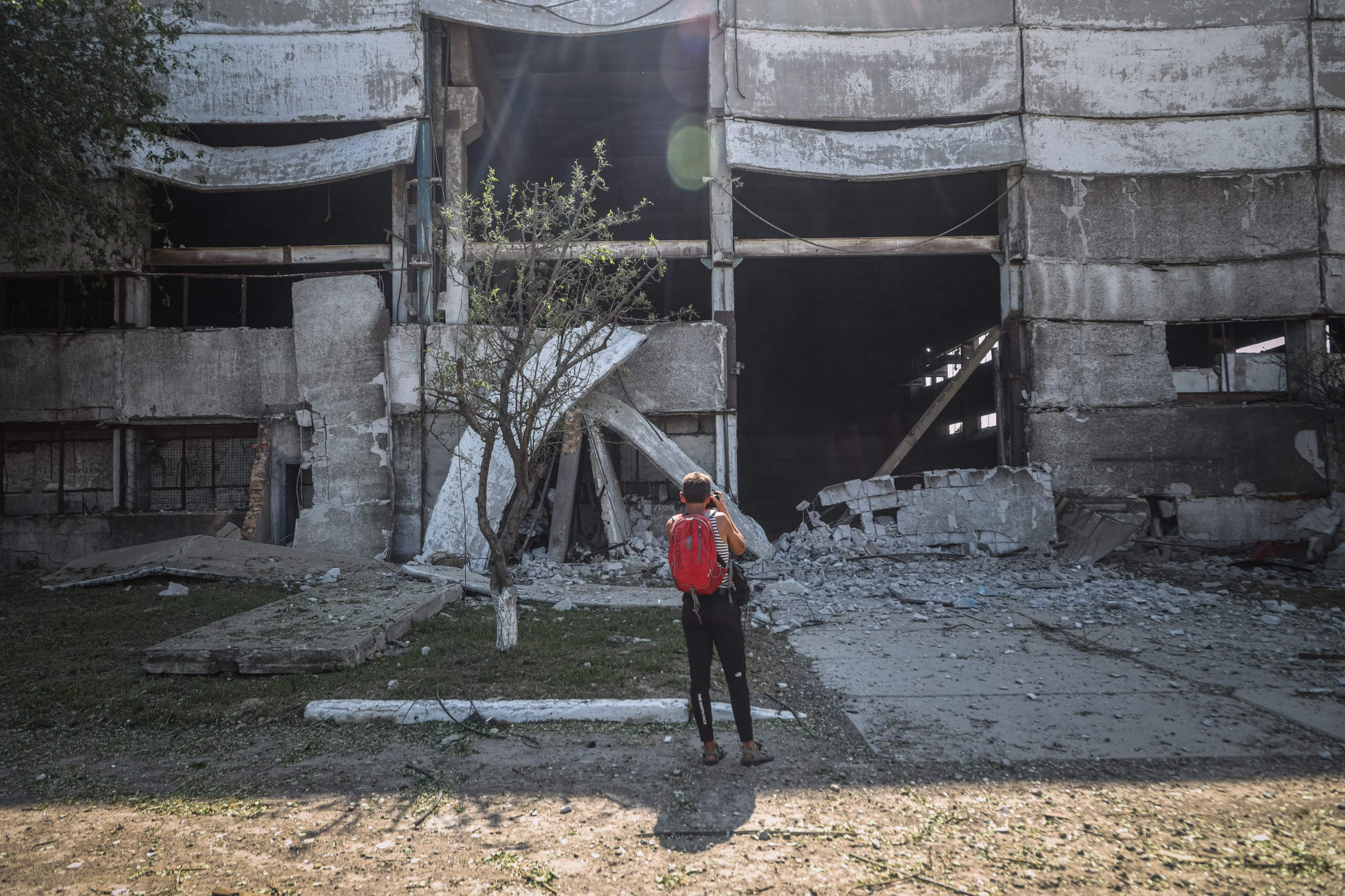  Homem tira foto de um prédio industrial na Ucrânia destruído por um míssil russo nesta quinta-feira (18)