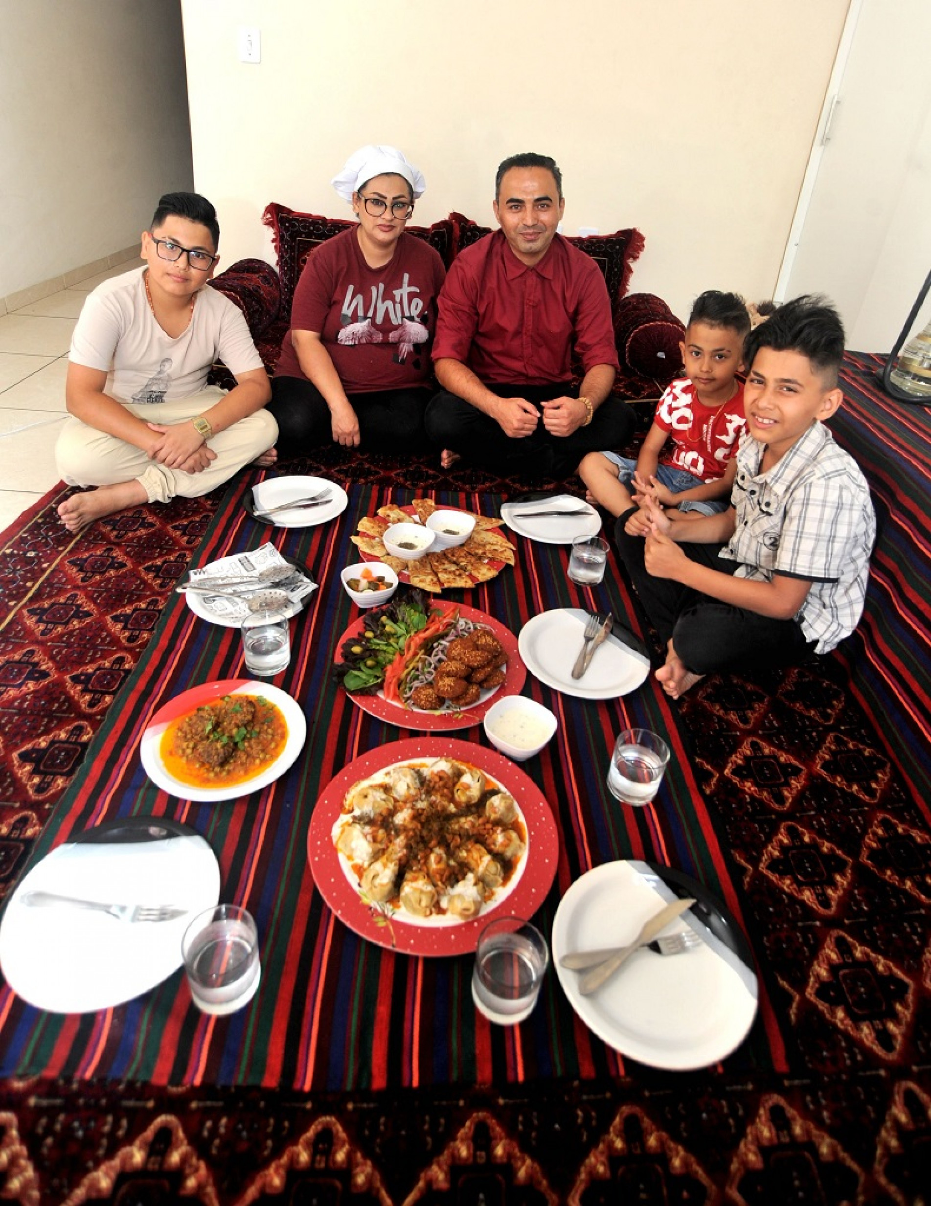 Mesmo longe do seu país, Zakia e Sohrab Samim -- com os três filhos pequenos -- mantêm a tradição de receber visitantes com pratos típicos sobre um autêntico tapete persa