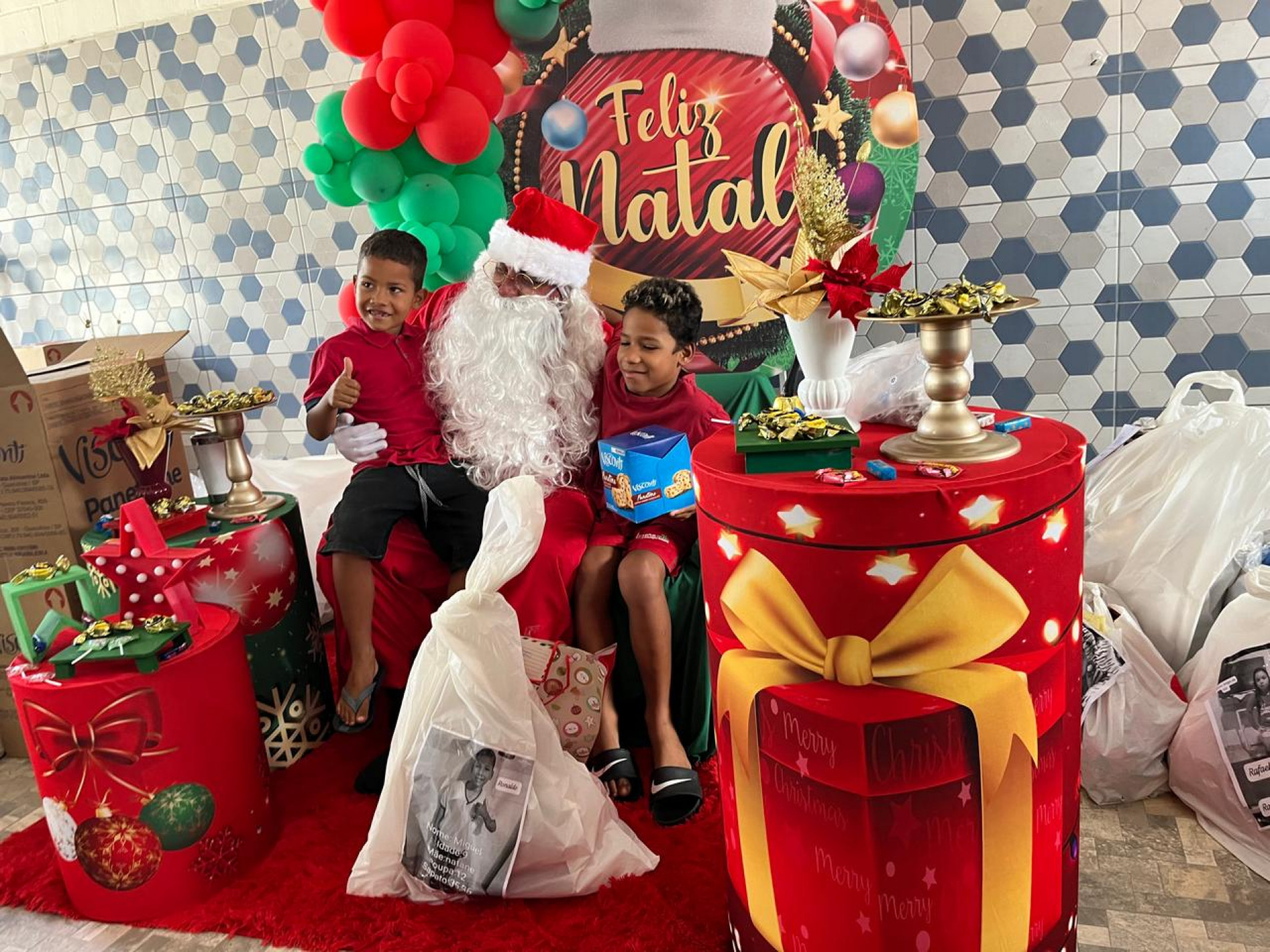 Sentado em poltrona, o personagem começou a receber as crianças que eram anunciadas pelo grupo de voluntários.