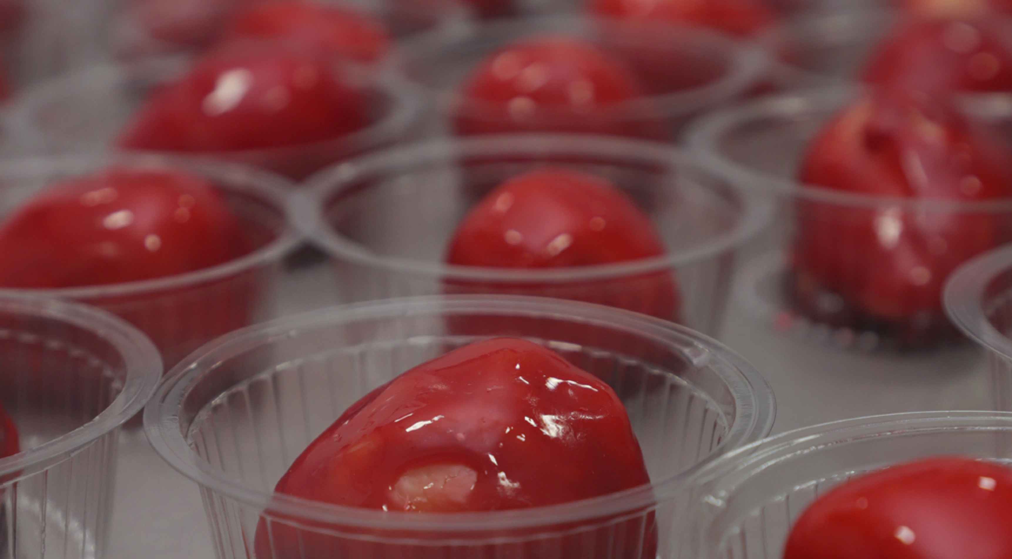 Fruta é coberta com camadas de brigadeiro branco e calda vermelha brilhante