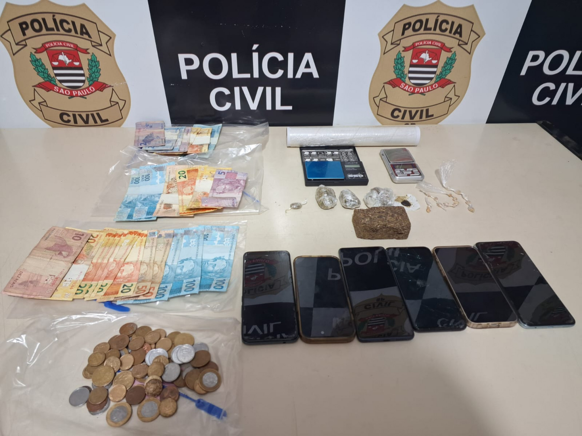 Foram apreendidas 16 pedras de crack, cinco grandes porções de maconha, seis aparelhos celulares, duas balanças de precisão, além de notas e moedas que somam aproximadamente R$ 1 mil