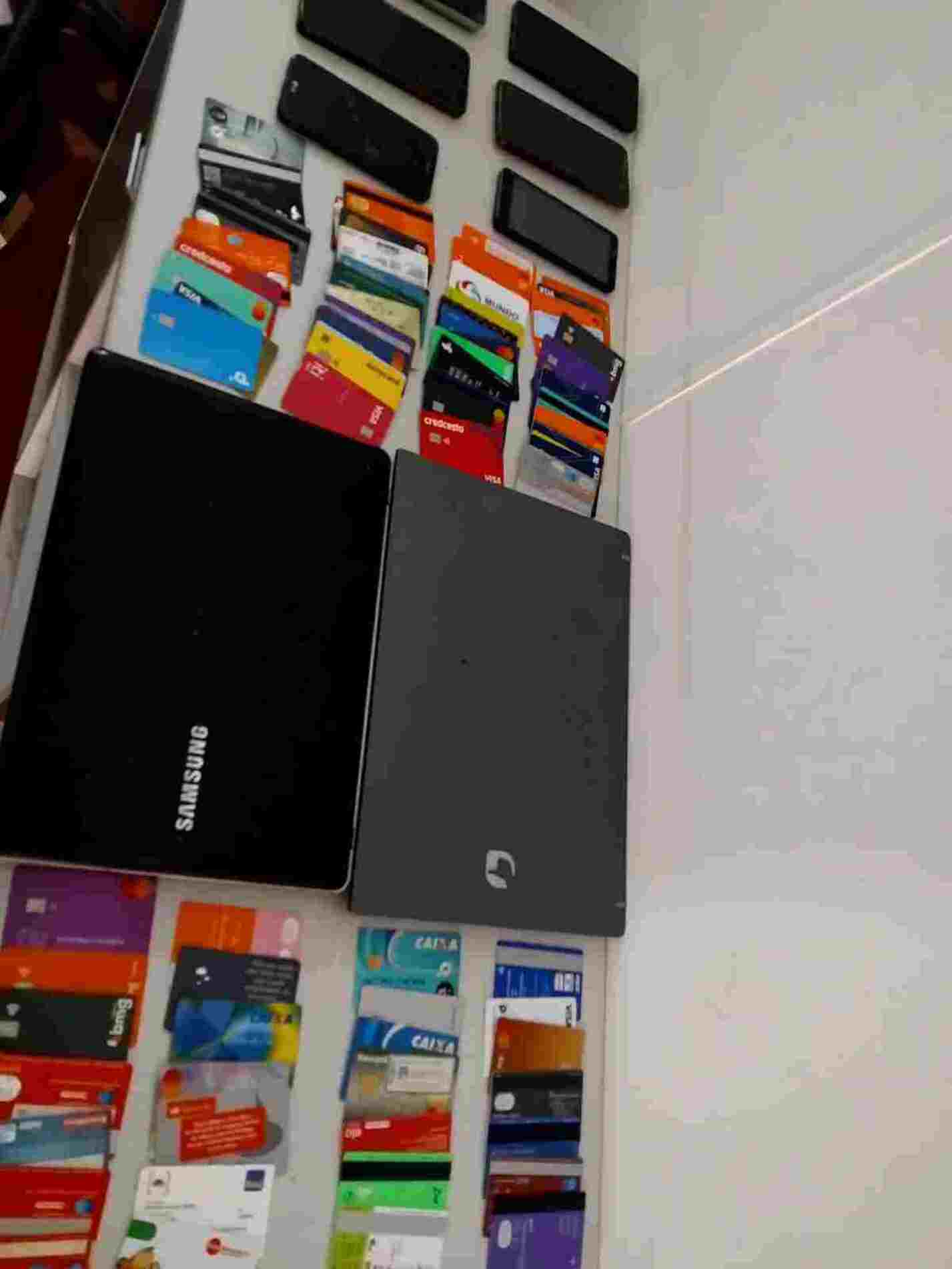 Os policiais apreenderam seis aparelhos celulares, dois notebooks, dezenas de cartões bancários e um caderno com anotações sobre controle de pagamentos
