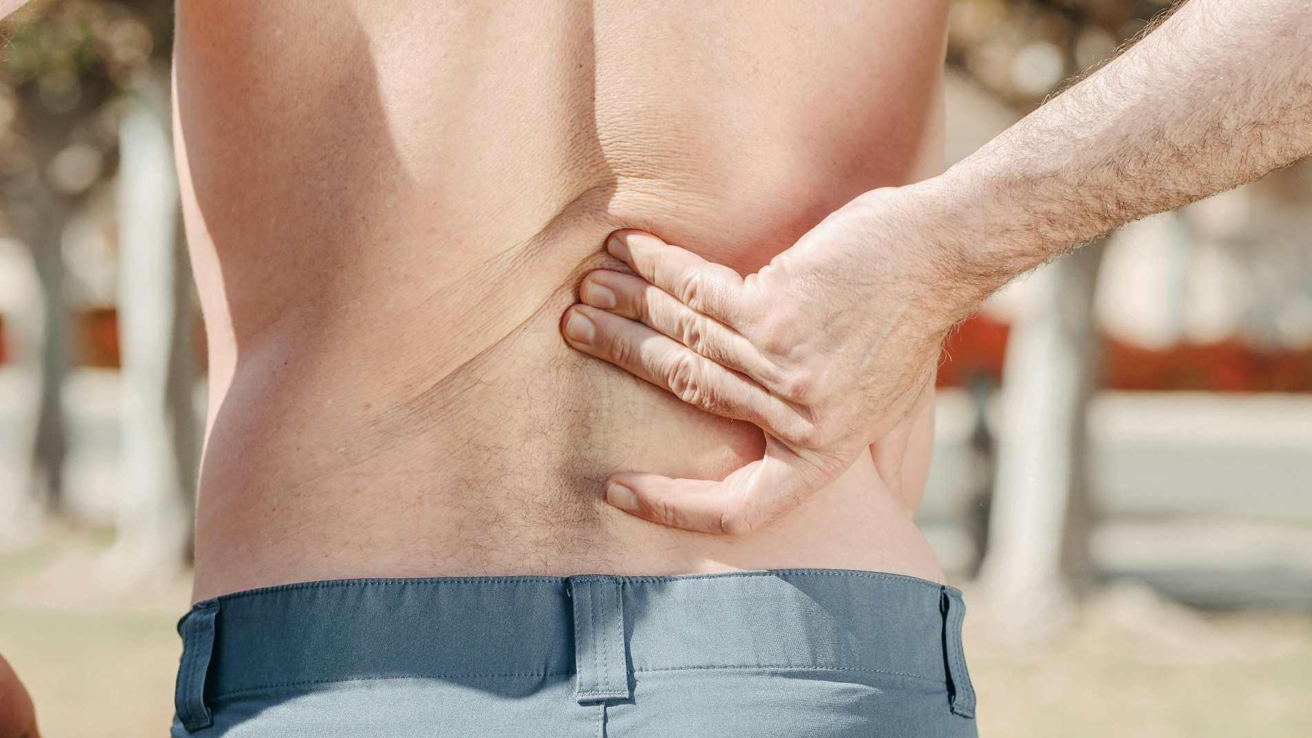 Homem apalpa as próprias costas com a mão direita