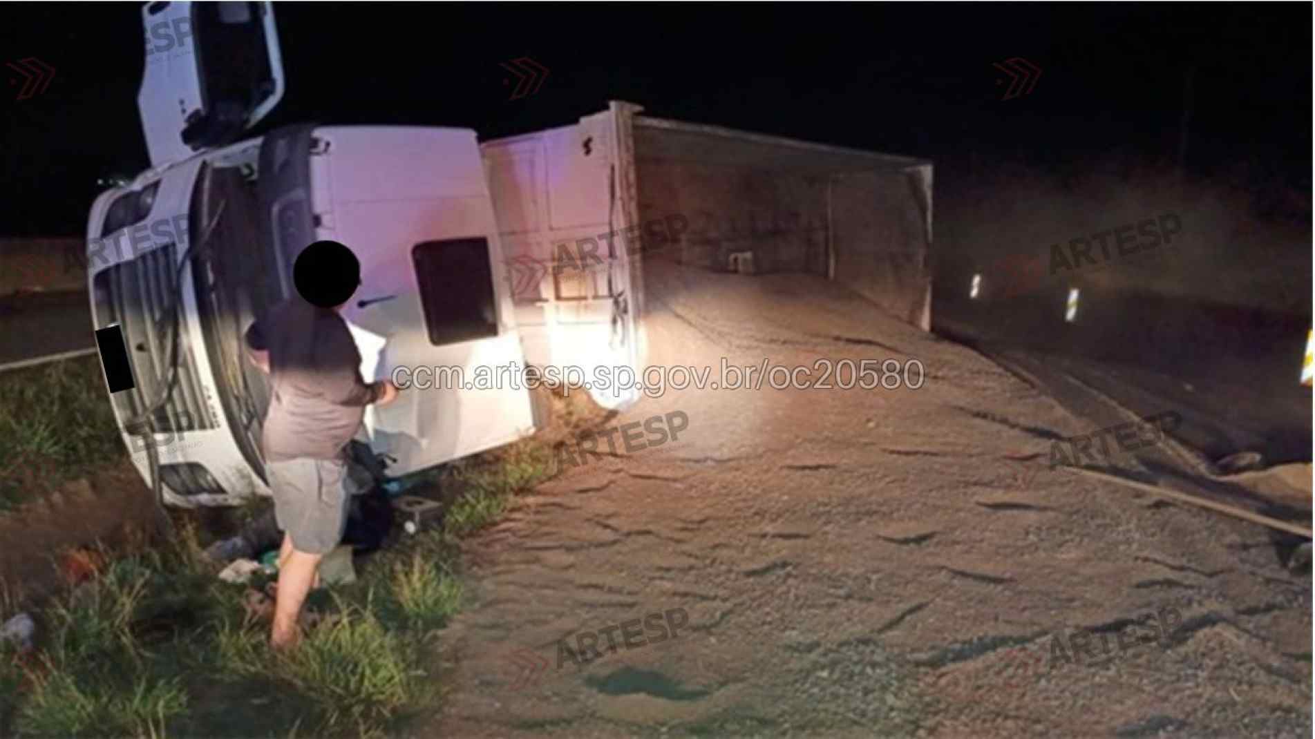 Caminhão em questão tombado e carga derramada sobre a pista 